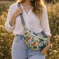 Handmade cross body bag Elara Wildflower Path in ANIMAL PRINT worn by woman in a field.