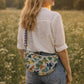 Handmade cross body bag Elara Wildflower Path in ANIMAL PRINT worn by woman in a field.