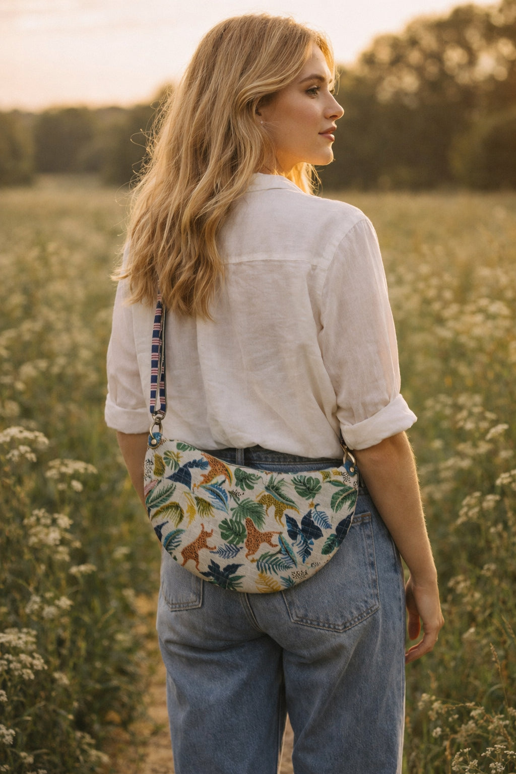 Handmade cross body bag Elara Wildflower Path in ANIMAL PRINT worn by woman in a field.