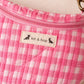 Handmade cross body bag Elara in pink gingham worn by a woman outdoors in a sunny field.