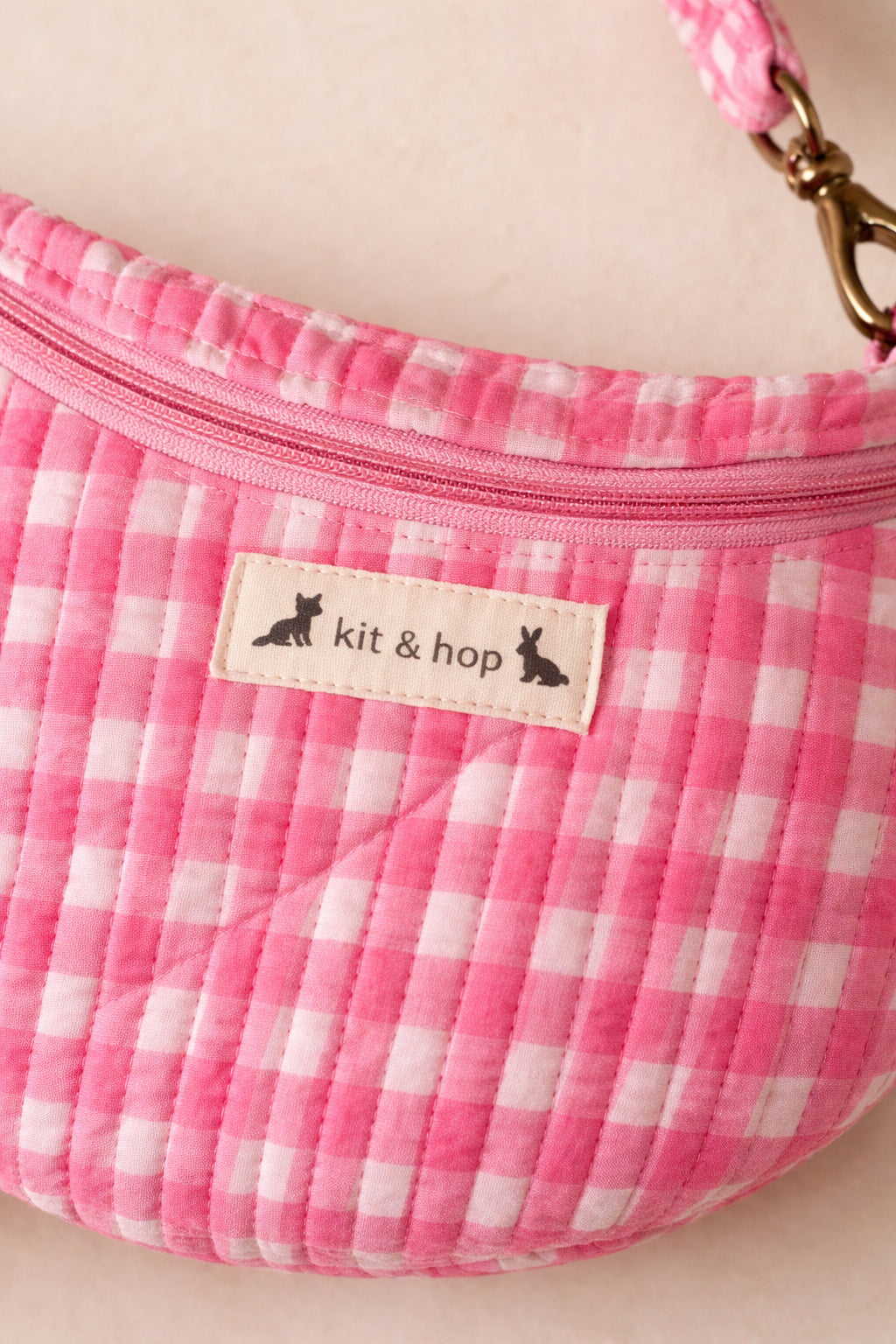 Handmade cross body bag Elara in pink gingham worn by a woman outdoors in a sunny field.