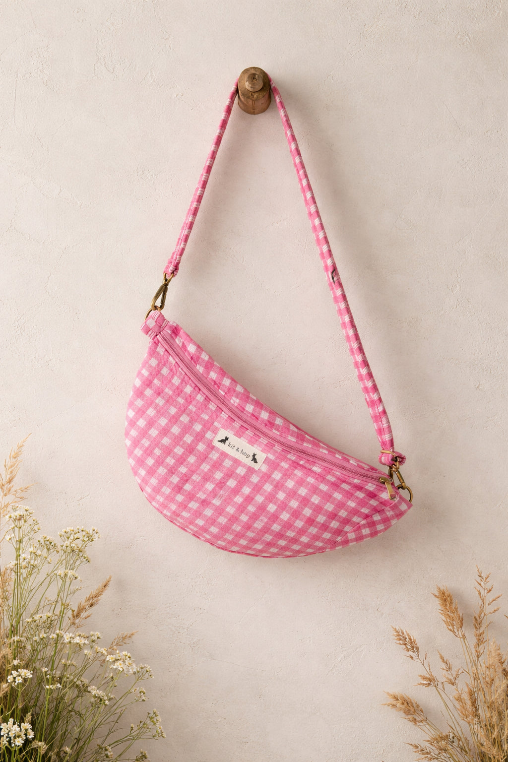 Handmade cross body bag Elara in pink gingham worn by a woman outdoors in a sunny field.