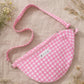 Handmade cross body bag Elara in pink gingham worn by a woman outdoors in a sunny field.