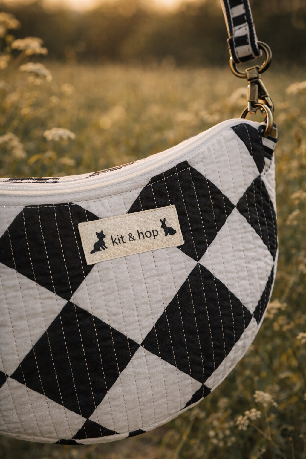 Handmade cross body bag Elara Wildflower Path in noir check worn by woman in a field.