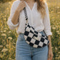 Handmade cross body bag Elara Wildflower Path in noir check worn by woman in a field.