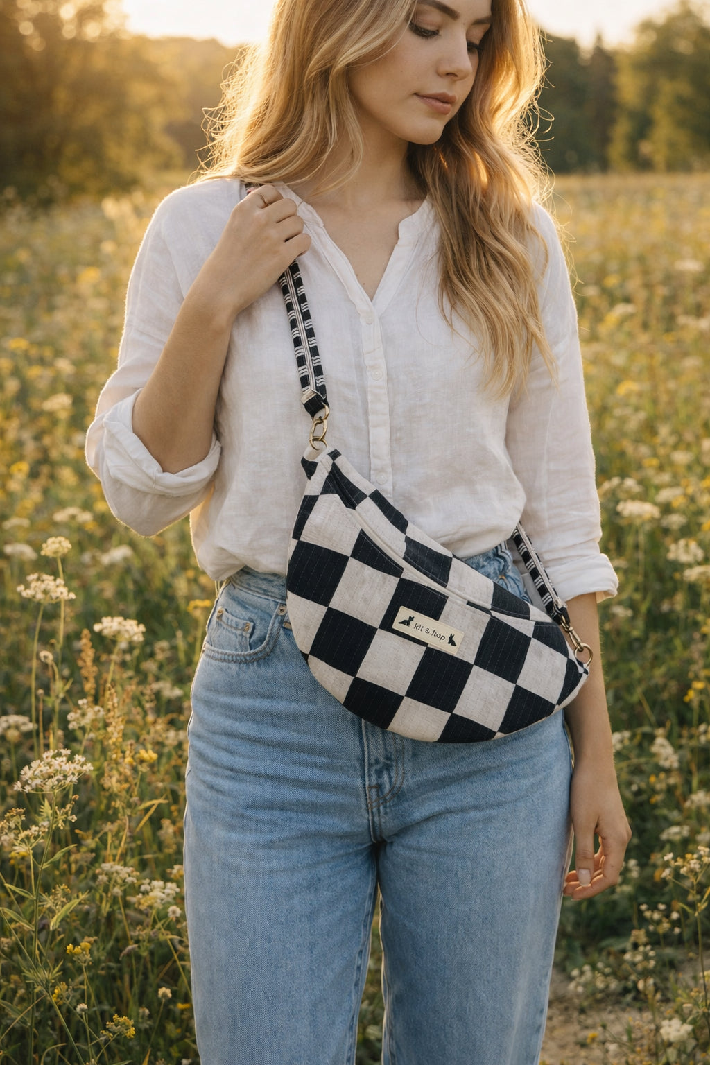 Handmade cross body bag Elara Wildflower Path in noir check worn by woman in a field.