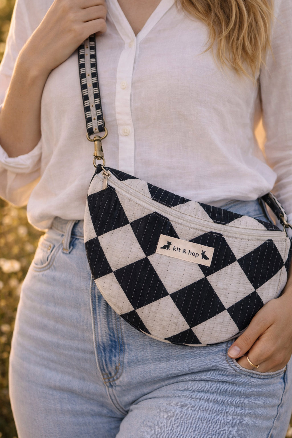 Handmade cross body bag Elara Wildflower Path in noir check worn by woman in a field.