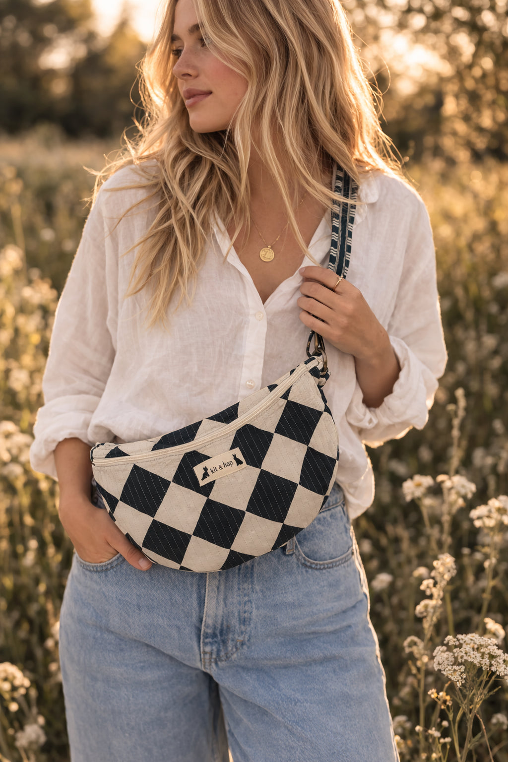 Handmade cross body bag Elara Wildflower Path in noir check worn by woman in a field.