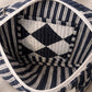 Handmade cross body bag Elara Wildflower Path in noir check worn by woman in a field.