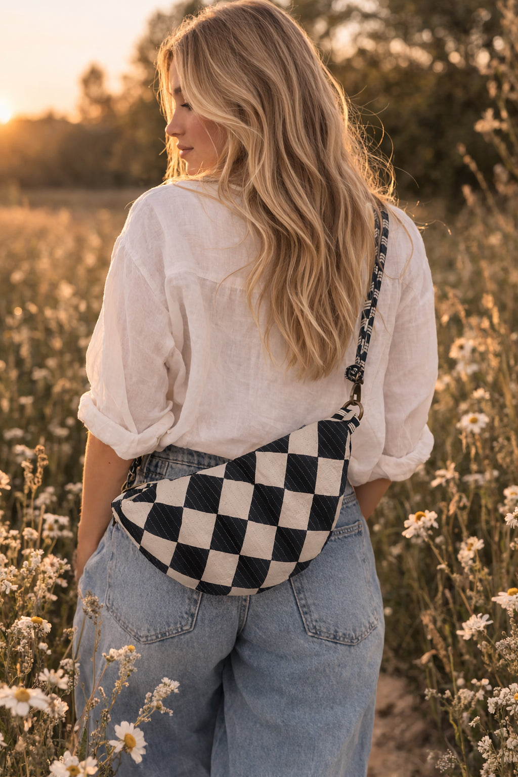 Handmade cross body bag Elara Wildflower Path in noir check worn by woman in a field.