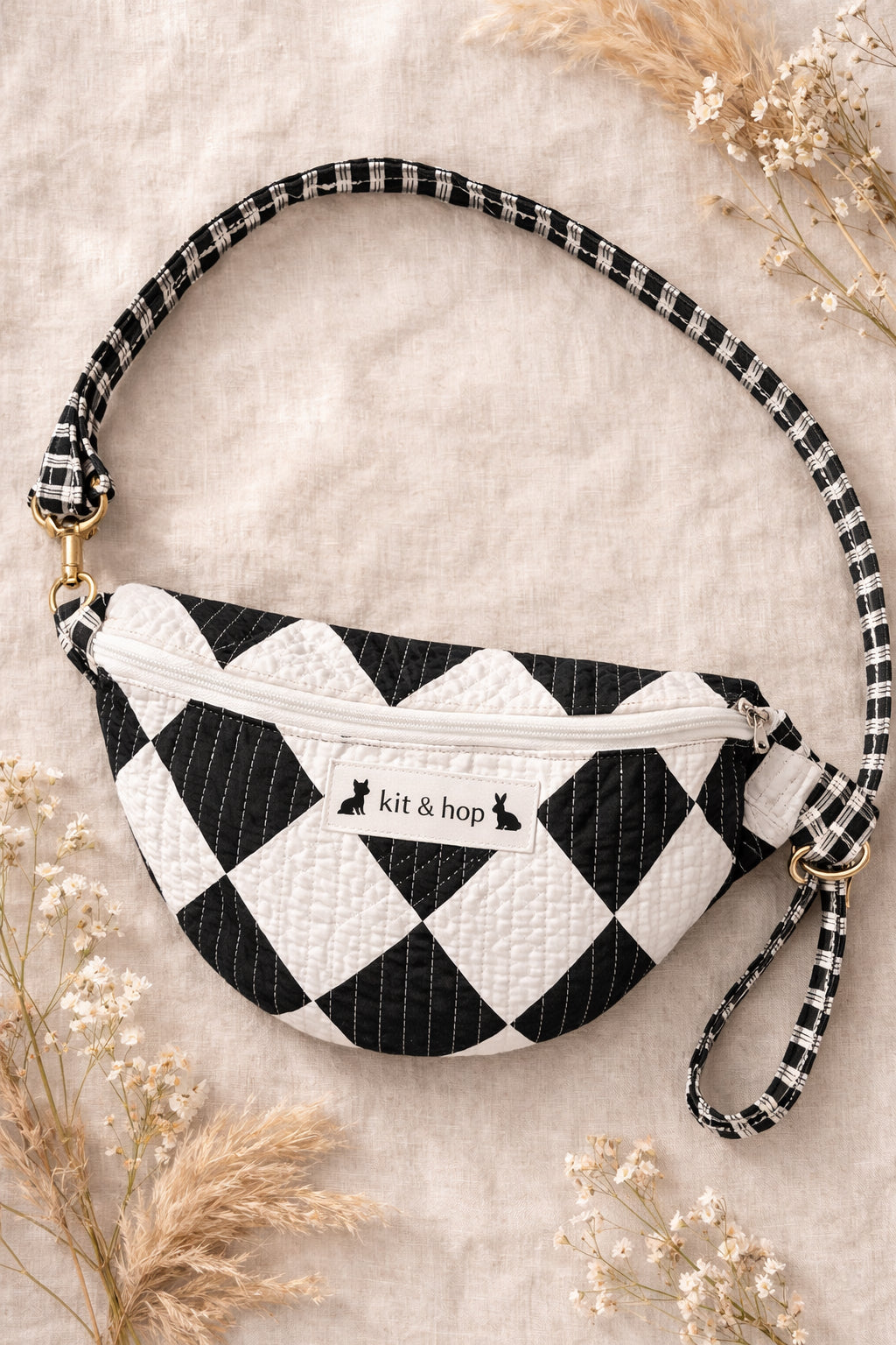 Handmade cross body bag Elara Wildflower Path in noir check worn by woman in a field.