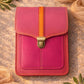 Handmade Leather Crossbody Bag in vibrant pink and orange tones, set against a textured background with greenery.
