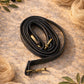 Handmade Leather Crossbody Bag strap displayed on a soft, textured surface with decorative olive leaves.
