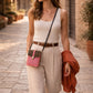 Woman walking in a stylish outfit with a Handmade Leather Crossbody Bag on a cobblestone street.