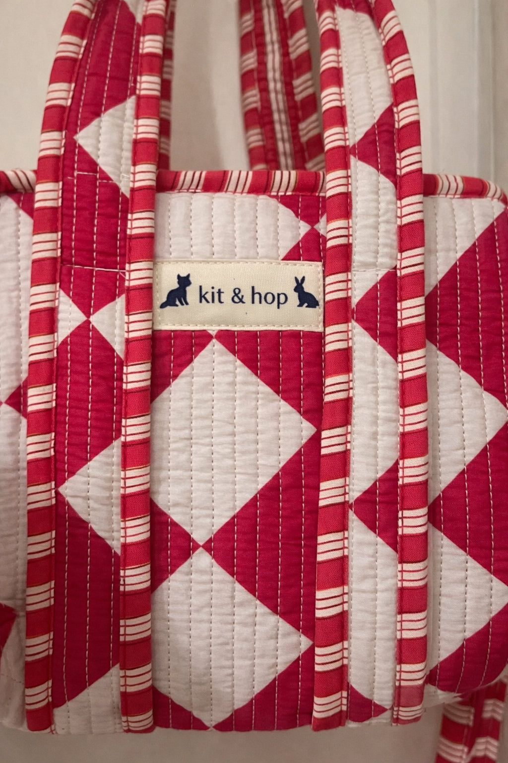 Handmade Cotton Mini Tote Bag with red and white diamond pattern, hanging on a wall, showcasing its stylish design.