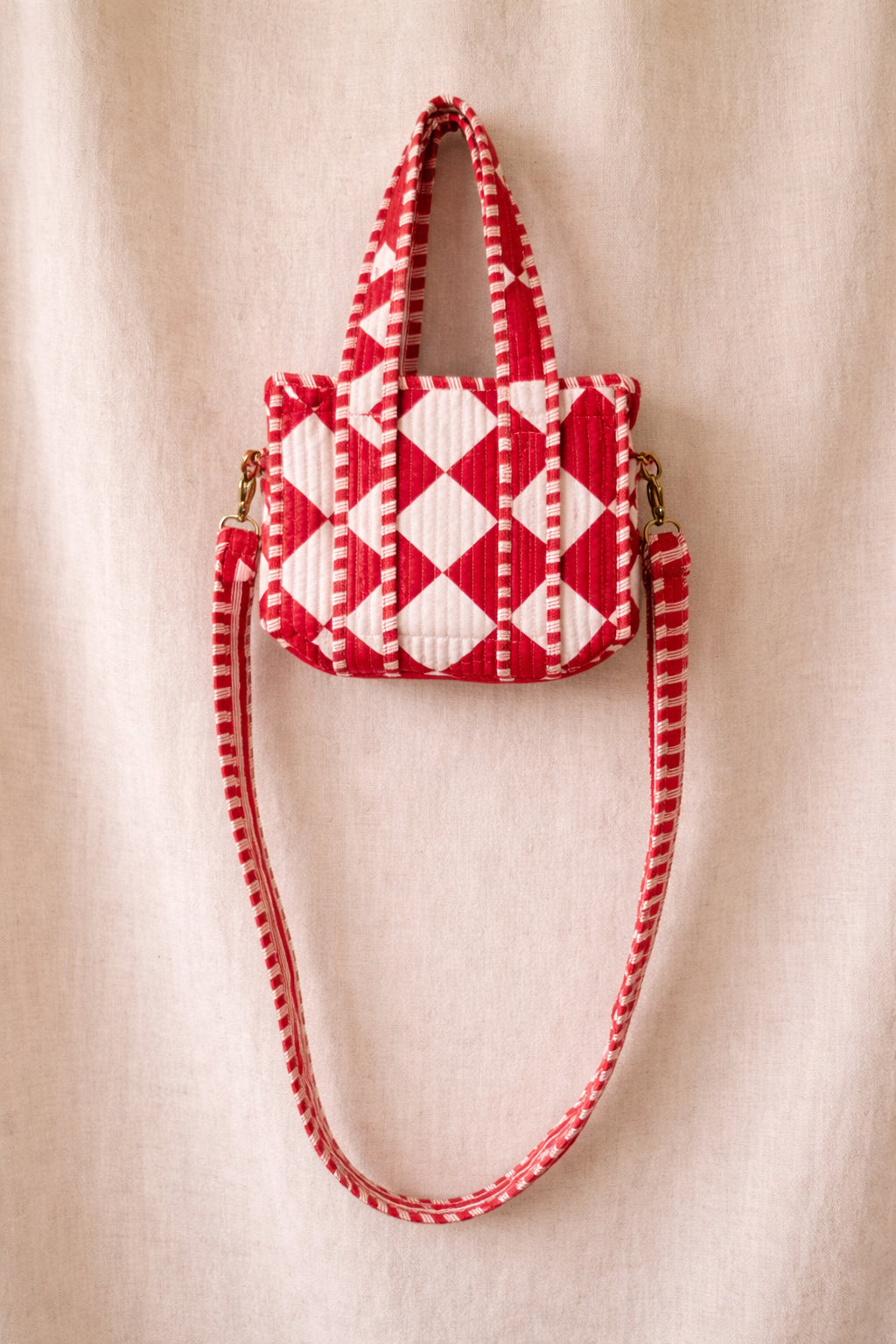 Handmade Cotton Mini Tote Bag with red and white diamond pattern, hanging on a wall, showcasing its stylish design.
