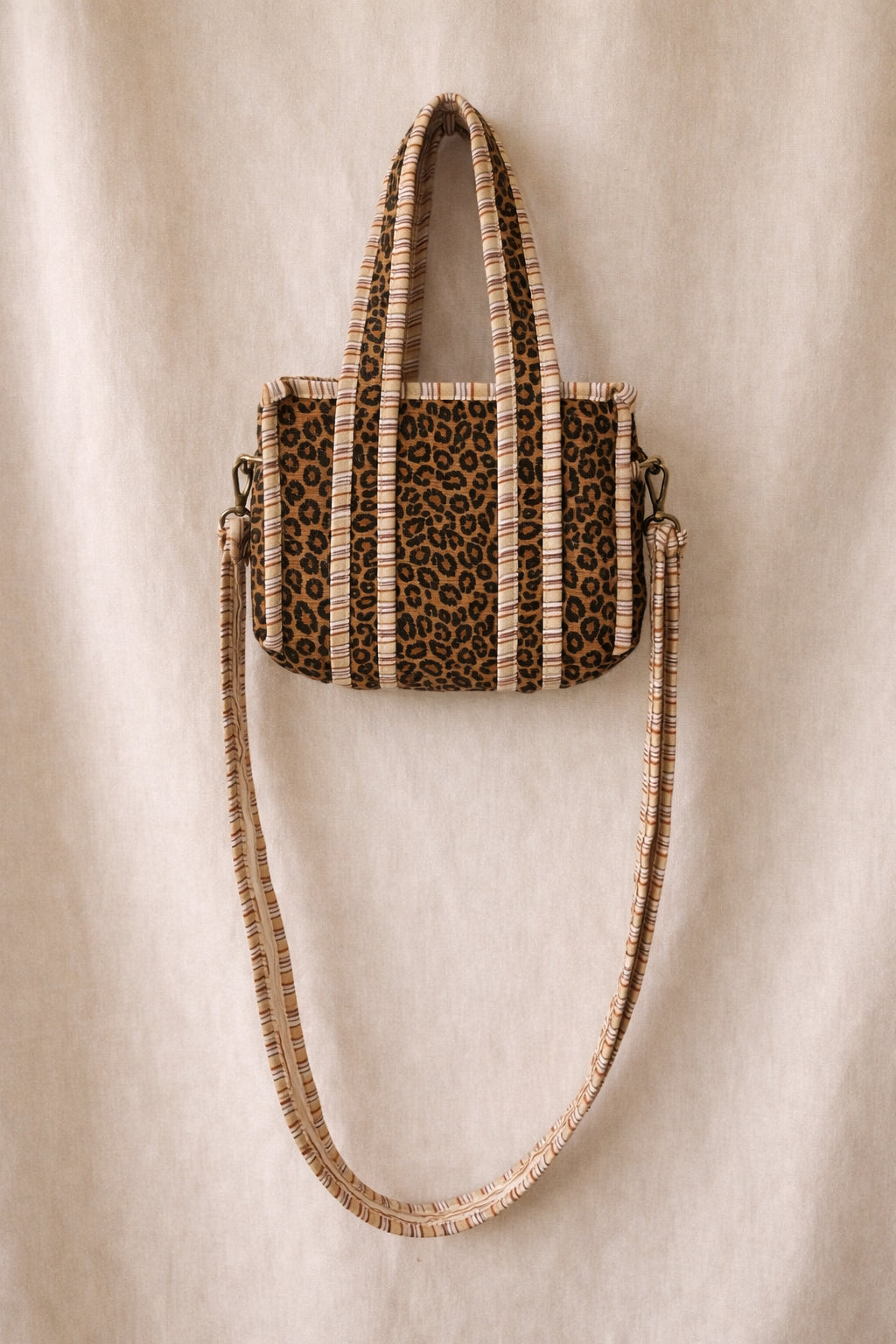 Handmade Cotton Mini Tote Bag - Lila - Wild Meadow -Sable with a stylish leopard print design, hung on a wooden hook.