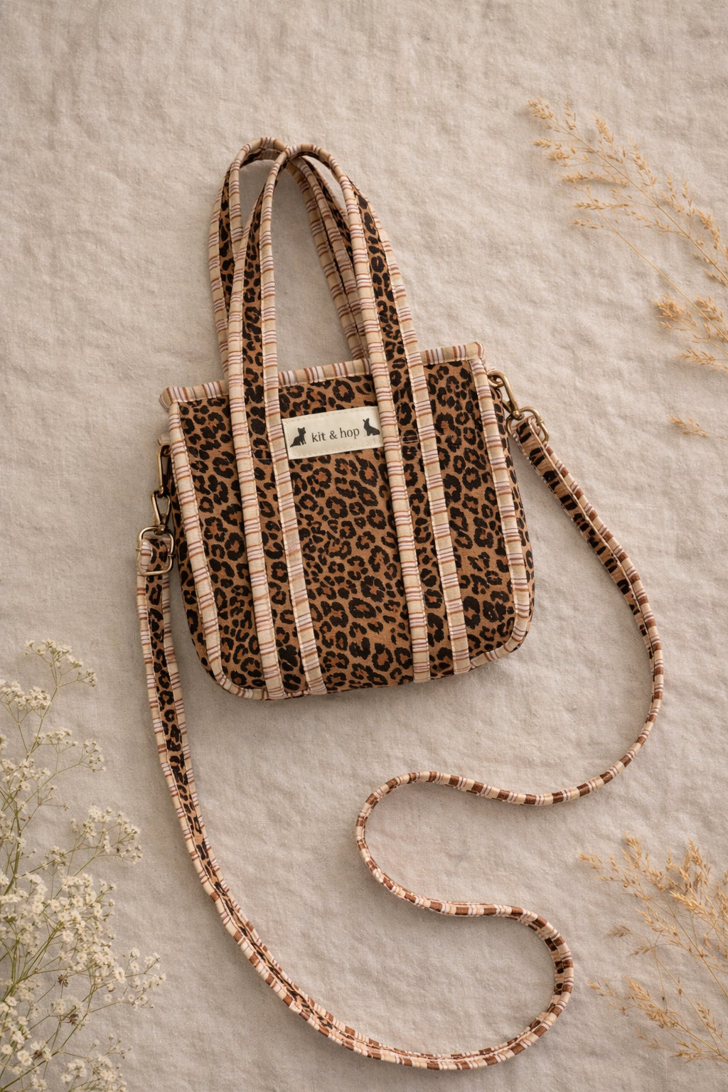 Handmade Cotton Mini Tote Bag - Lila - Wild Meadow -Sable with a stylish leopard print design, hung on a wooden hook.