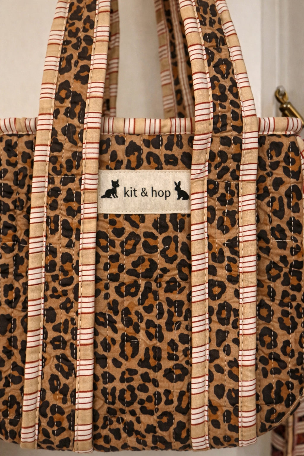 Handmade Cotton Mini Tote Bag - Lila - Wild Meadow -Sable with a stylish leopard print design, hung on a wooden hook.