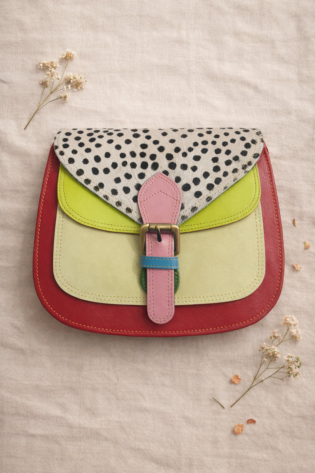 Handmade Leather Crossbody Bag - Romy in colorful leather with unique pattern and pink buckle, showcasing sustainable craftsmanship.