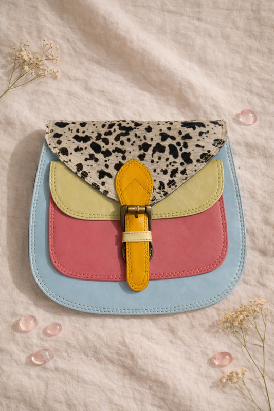 Handmade Leather Crossbody Bag featuring colorful patches of pink, blue, yellow, and a spotted flap on a soft background.