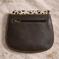Handmade Leather Crossbody Bag featuring colorful patches of pink, blue, yellow, and a spotted flap on a soft background.