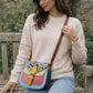 Handmade Leather Crossbody Bag featuring colorful patches of pink, blue, yellow, and a spotted flap on a soft background.