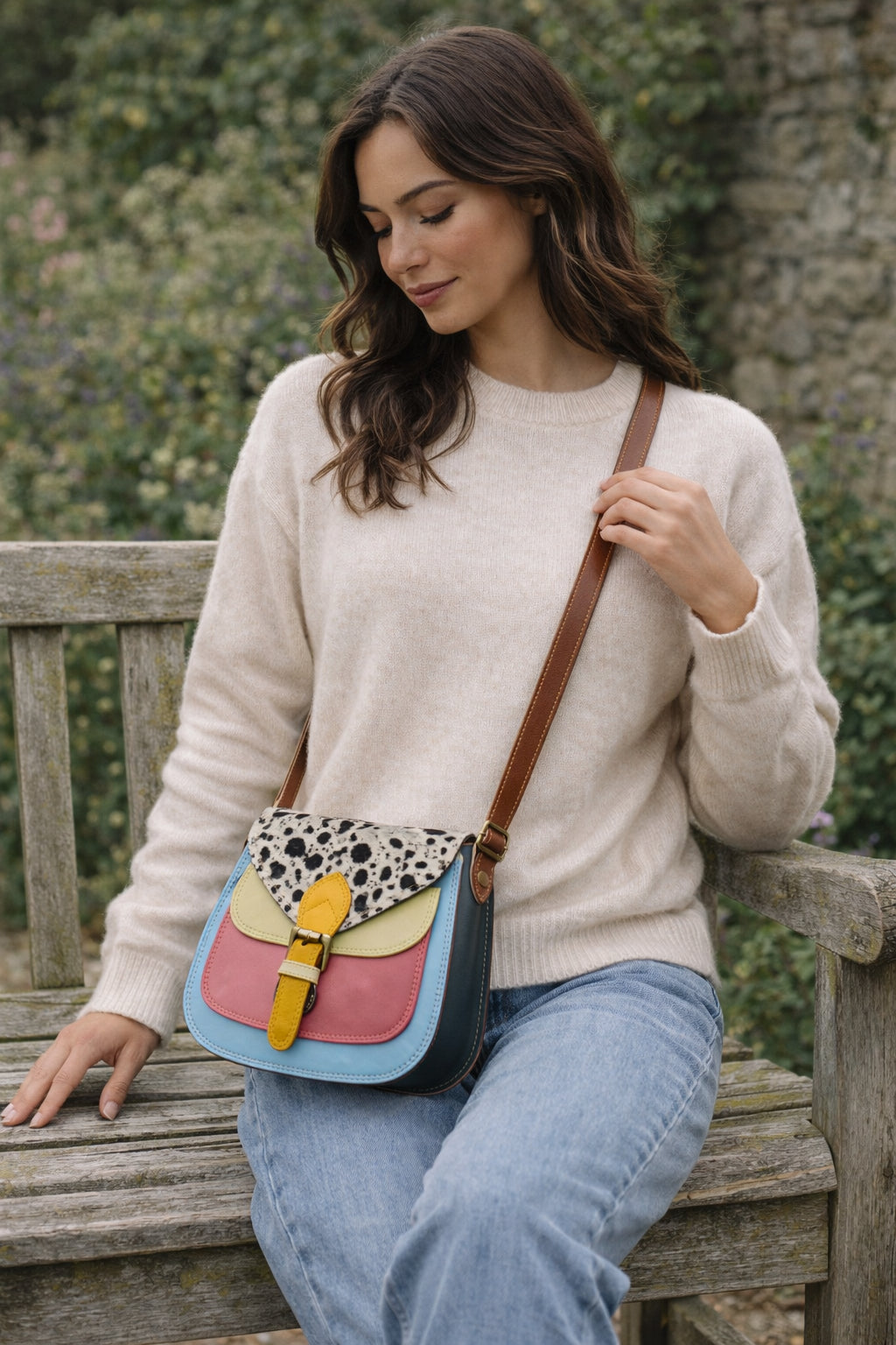 Handmade Leather Crossbody Bag featuring colorful patches of pink, blue, yellow, and a spotted flap on a soft background.