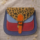 Handmade Leather Crossbody Bag - Romy in vibrant colors with leopard print flap, showcasing unique design and sustainability.