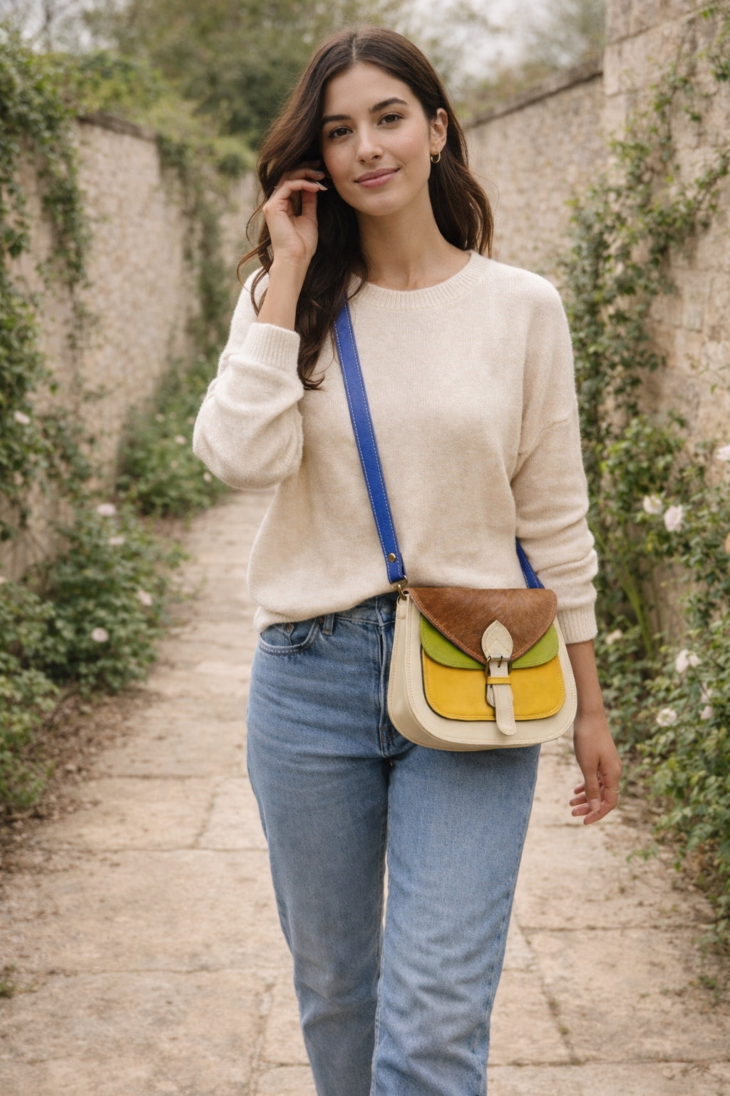 Handmade Leather Crossbody Bag - Romy - Walled Garden - Primrose displayed on soft fabric with flower petals around.