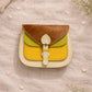 Handmade Leather Crossbody Bag - Romy - Walled Garden - Primrose displayed on soft fabric with flower petals around.