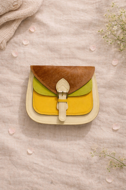 Handmade Leather Crossbody Bag - Romy - Walled Garden - Primrose displayed on soft fabric with flower petals around.