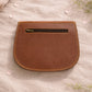 Handmade Leather Crossbody Bag - Romy - Walled Garden - Primrose displayed on soft fabric with flower petals around.