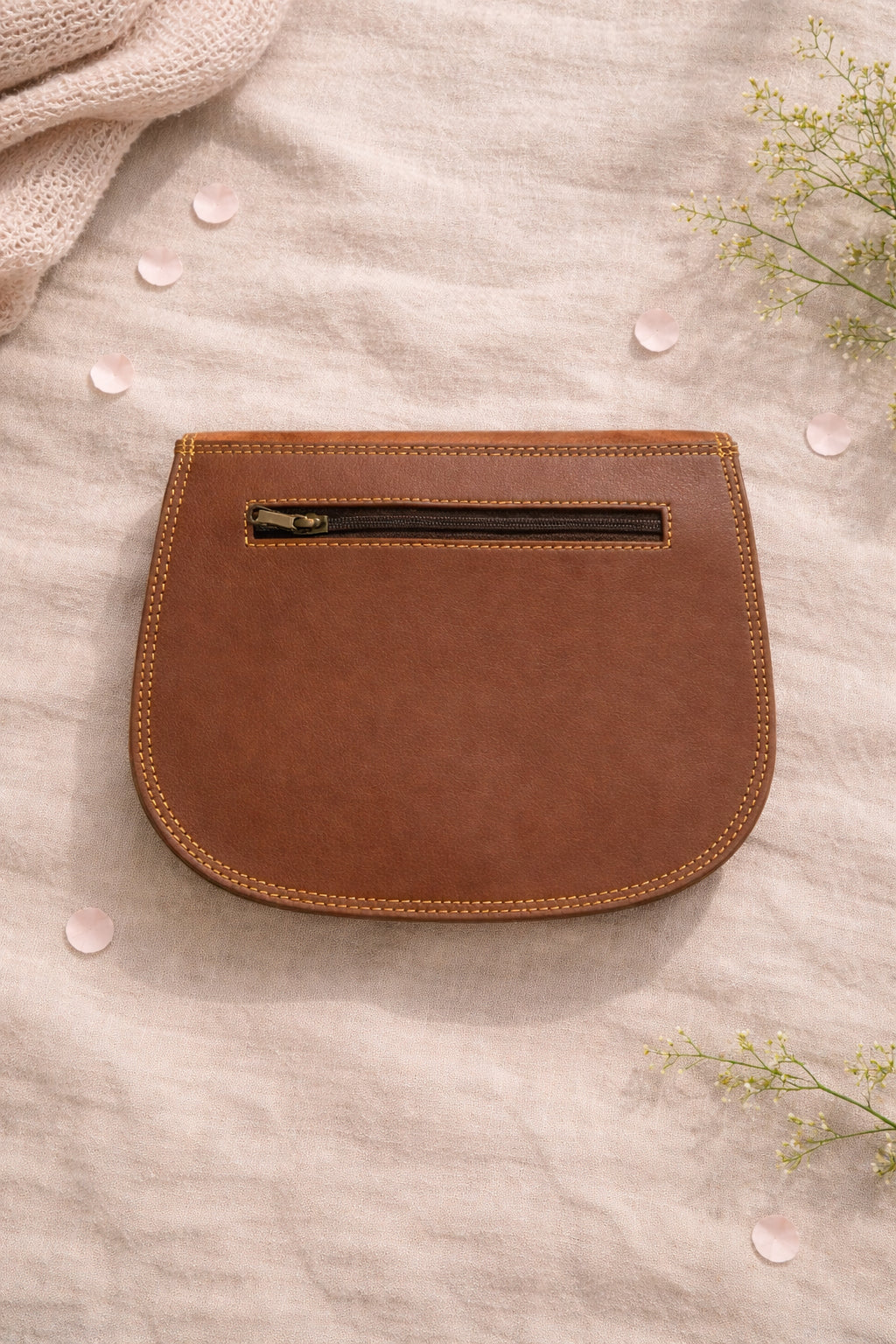 Handmade Leather Crossbody Bag - Romy - Walled Garden - Primrose displayed on soft fabric with flower petals around.