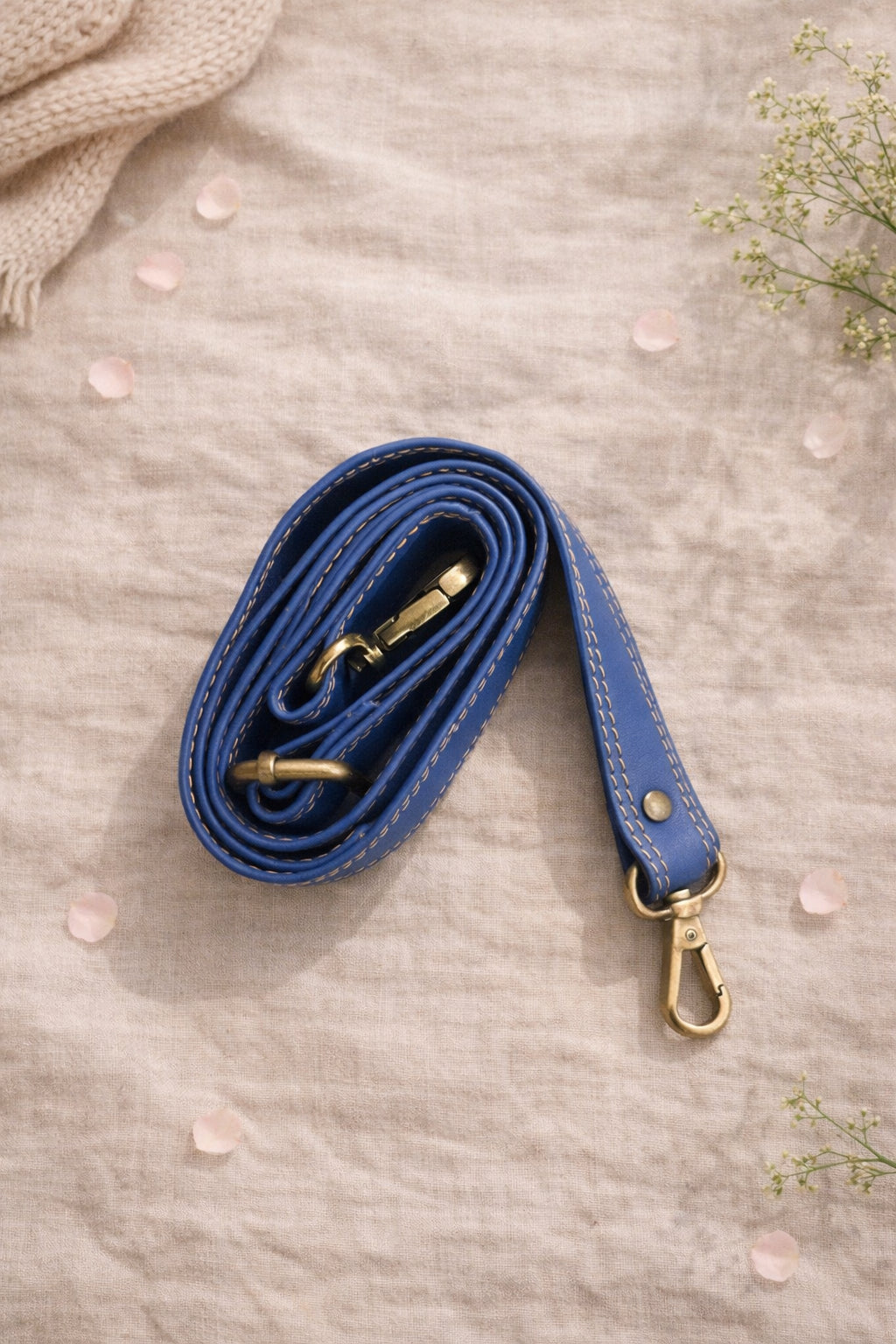 Handmade Leather Crossbody Bag - Romy - Walled Garden - Primrose displayed on soft fabric with flower petals around.