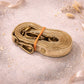 Handmade Leather Crossbody Bag strap in metallic gold color, elegantly coiled on a sparkling surface.