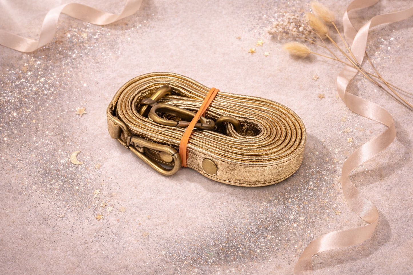 Handmade Leather Crossbody Bag strap in metallic gold color, elegantly coiled on a sparkling surface.