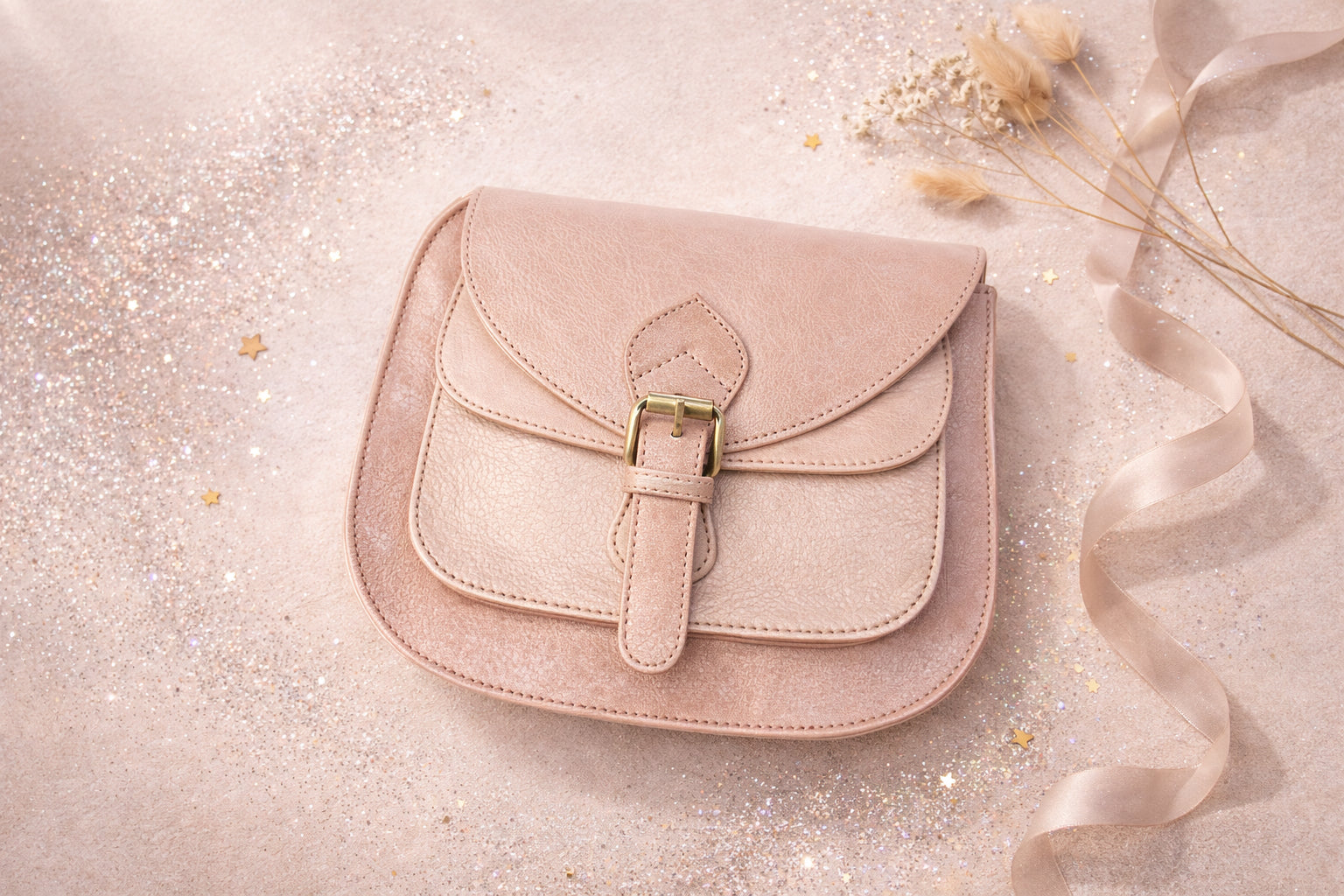 Handmade Leather Crossbody Bag - Romy - Petal resting on a sparkling surface with delicate flowers and ribbon.