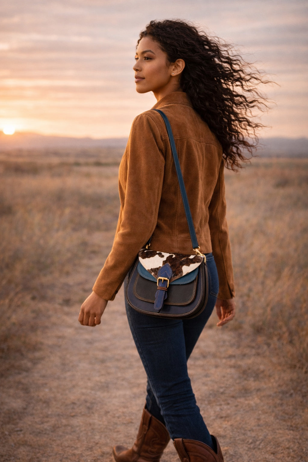 Model wearing a Handmade Leather Crossbody Bag, the Romy, in a scenic outdoor setting at sunrise.