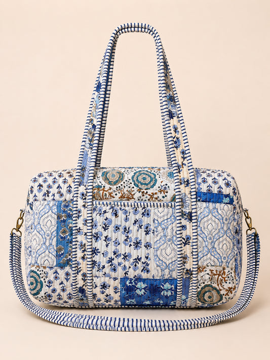 Model carrying a handmade patchwork duffle bag in a colorful flower field under a bright blue sky.