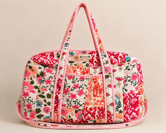 Model carrying a handmade patchwork duffle bag in a colorful flower field under a bright blue sky.