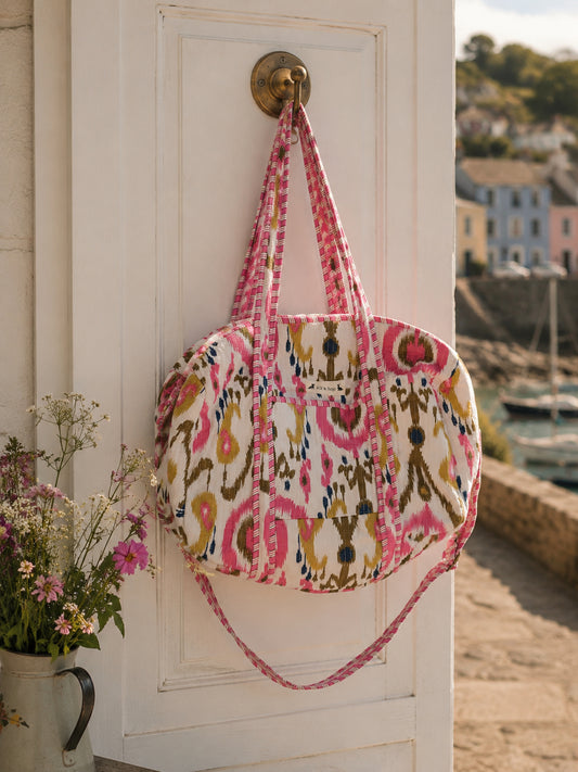 Handmade duffle bag hanging on a door, featuring a colorful pattern and practical design, perfect for travel and adventure.